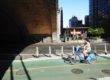 Woman on a Bicycle Riding under the Queensboro Bridge - Manhattan, New York City